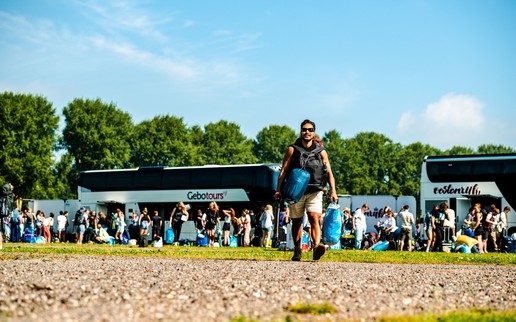 Lowlandsbezoeker stapt met bagage uit een touringcar